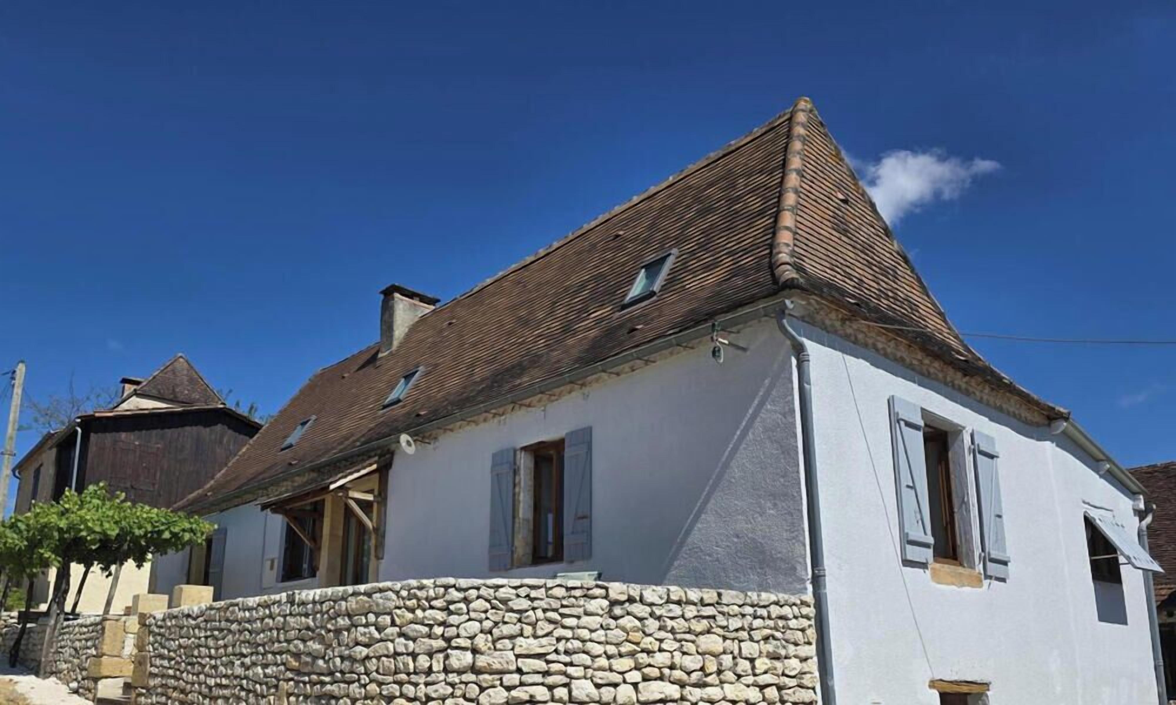 A traditional stone house with a sloped roof and a stone foundation.