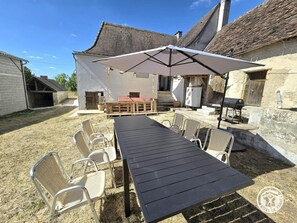 Un patio exterior con una mesa y sillas, una parrilla y una zona de estar cubierta.