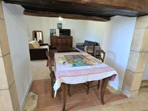 A dining area with a table set for two, a sofa, and a television in the background. - Large cottage, parking, pets welcome - 10 guests (Bars)