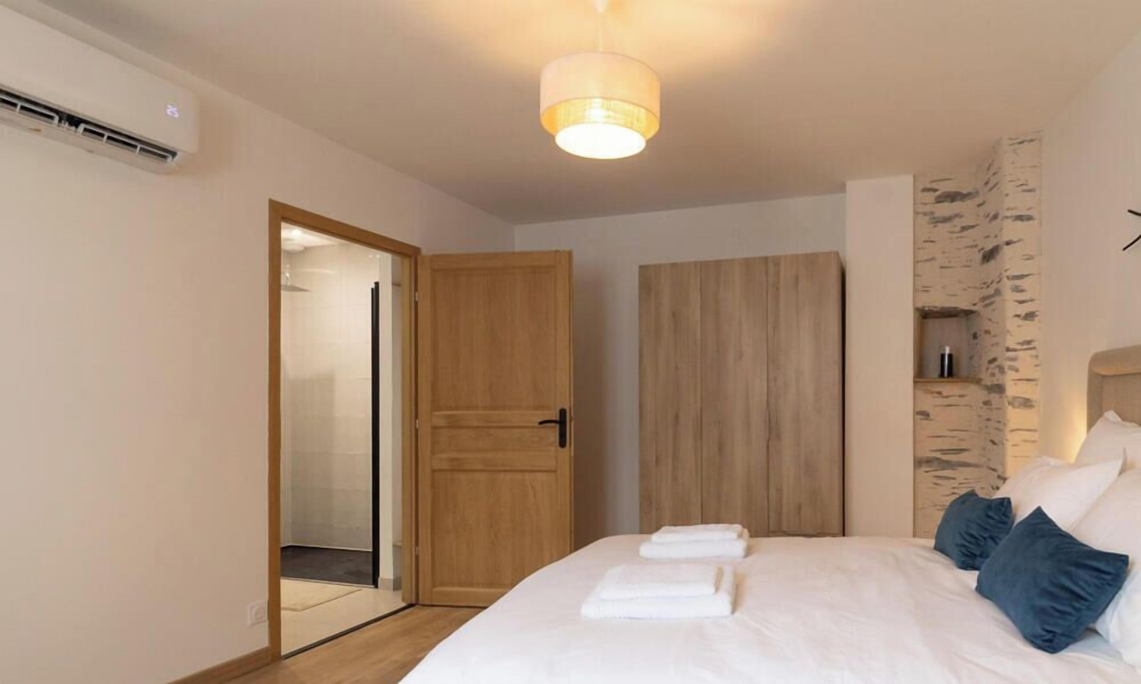 Un dormitorio con cama, armario de madera, espejo y lámpara en el techo.