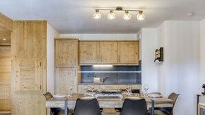Et moderne køkken med træskabe, et spisebord dækket til fire og en indbygget komfur.