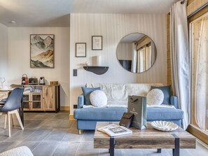 Ein modernes Wohnzimmer mit einem blauen Sofa, einem Couchtisch und einem Essbereich mit einem Holzschrank.