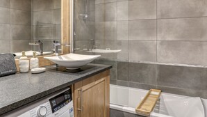 Et moderne badeværelse med et fristående badekar, en glas brusekabine og et toiletbord med vask og spejl.