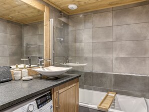 Ein modernes Badezimmer mit freistehender Badewanne, einer Duschkabine aus Glas und einem Waschtisch mit Spüle und Spiegel.