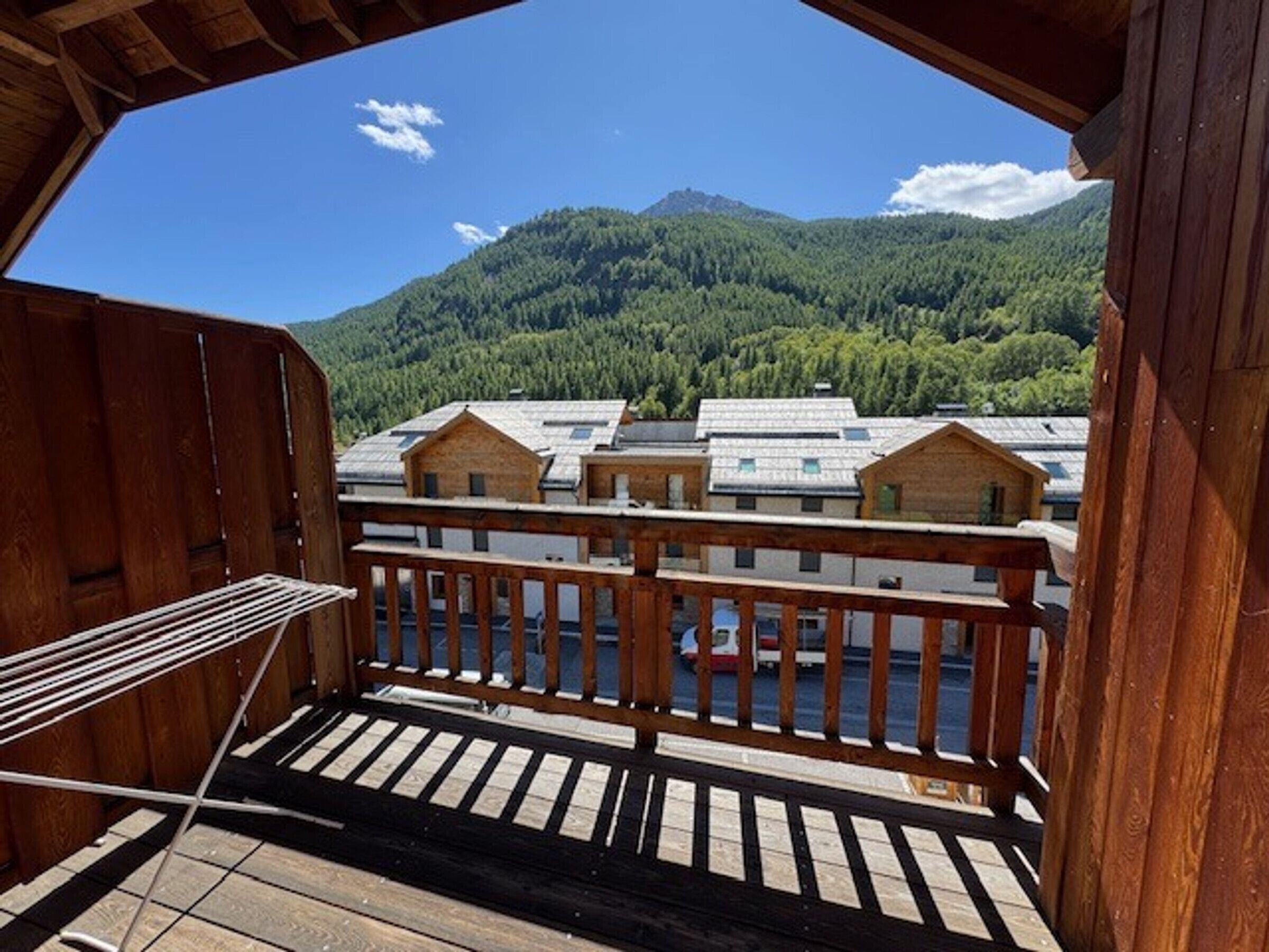 Una terraza de madera con vistas a un río y montañas boscosas.