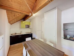 A compact kitchen with a wooden ceiling, a microwave, and a dining area with a table and chairs. - Bright apartment mountain view - 6 guests (Saint-Chaffrey)