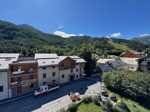 Un bâtiment avec un parking, un camion et un paysage montagneux en arrière-plan.