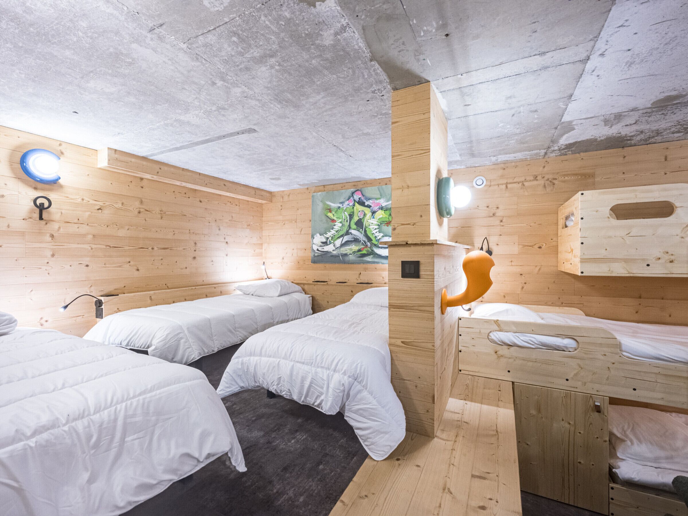 A room with wooden walls, two beds with white bedding, a painting on the wall, and a ceiling light fixture.