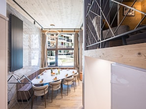 A modern dining area with a round table, chairs, and a view of the cityscape through large windows. - Luxury apartment - 10 guests (Tignes)