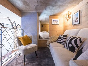 A cozy room with a sofa, a chair, a bed, and a wooden wall. - Luxury apartment - 10 guests (Tignes)