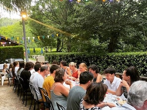 An outdoor dining area with tables and chairs, surrounded by greenery and trees. - Cozy chalet in La Gazonne - 5 guests (Sauveterre-de-Rouergue)