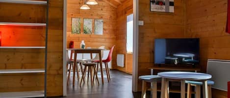 A wooden interior with a dining area, a television, and a painting on the wall.