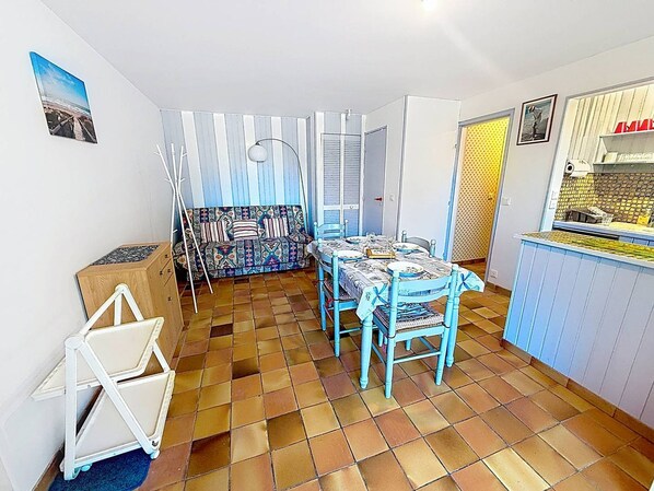 A compact living space with a dining area, a sofa, and a kitchenette. - Apartment with terrace - 5 guests (Merville-Franceville-Plage)