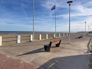 Une promenade en bord de mer avec un banc, des lampadaires et un drapeau.