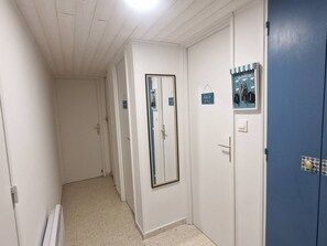 A corridor with doors, some with signs, and a blue door with a lock. - Apartment with AC, private parking - 4 guests (Balaruc-les-Bains)