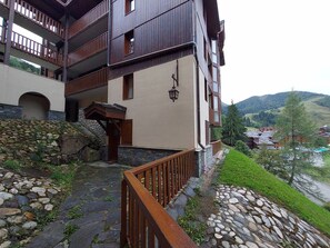 Ein mehrgeschossiges Gebäude mit Balkonen, Steinstufen und einer Steinmauer.