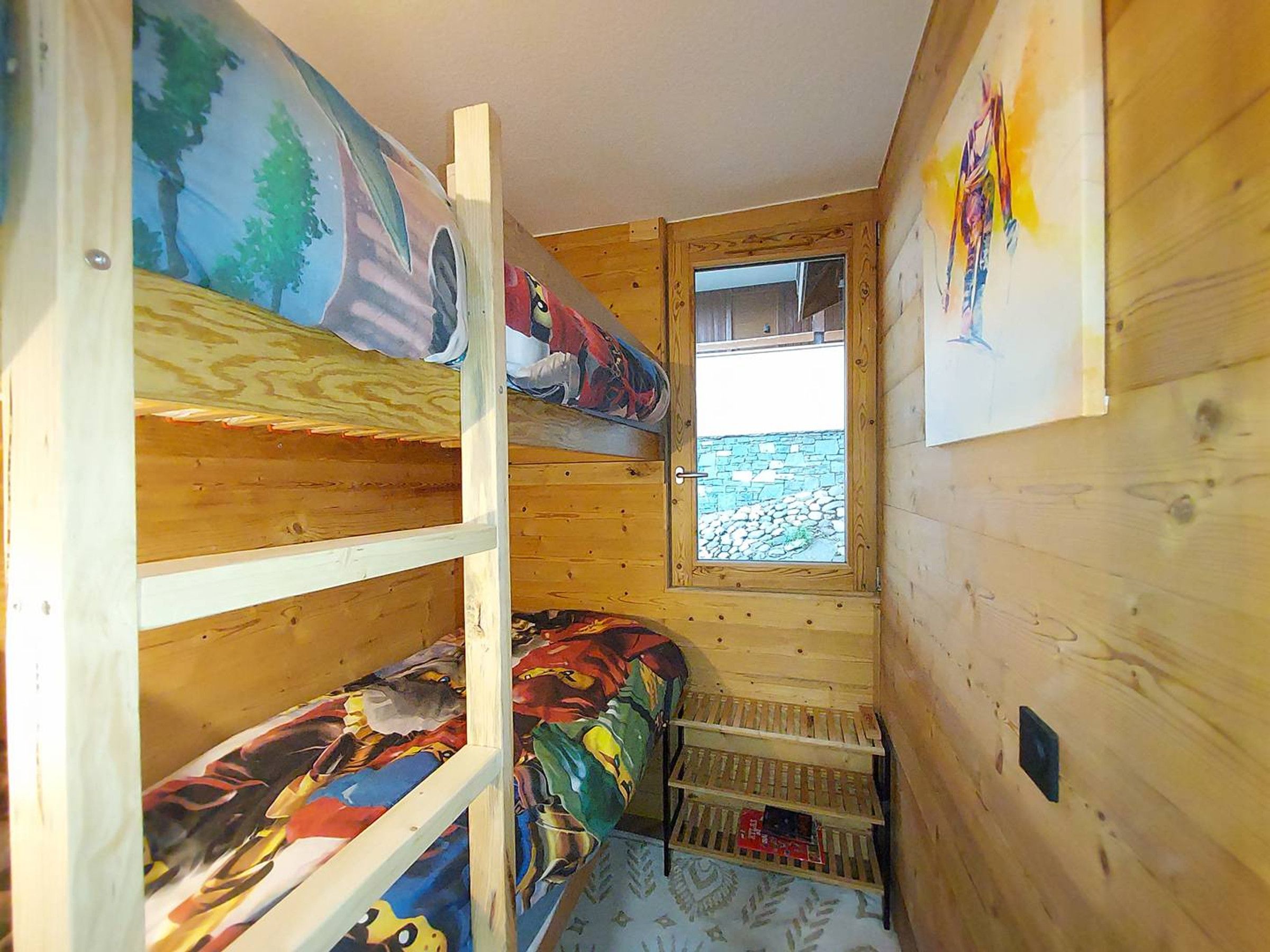 A cabin interior with bunk beds, a window with a view, and wooden walls.