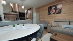 Eine moderne Küche mit Edelstahlgeräten, ein Essbereich mit einem runden Tisch und ein Wohnzimmer mit einer Couch und einem Bild an der Wand.