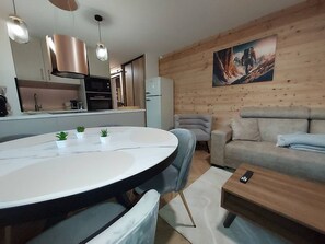Eine moderne Küche mit Edelstahlgeräten, ein Essbereich mit einem runden Tisch und ein Wohnzimmer mit einer Couch und einem Bild an der Wand.