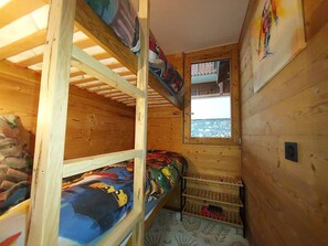 A compact wooden room with bunk beds, a small window, and a door leading outside. - Cozy apartment with panoramic view - 4 guests (Valmorel)