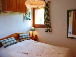A bedroom with a bed, a nightstand, a lamp, a window with curtains, and a mirror on the wall. - Practical apartment - 6 guests (Arêches-Beaufort)