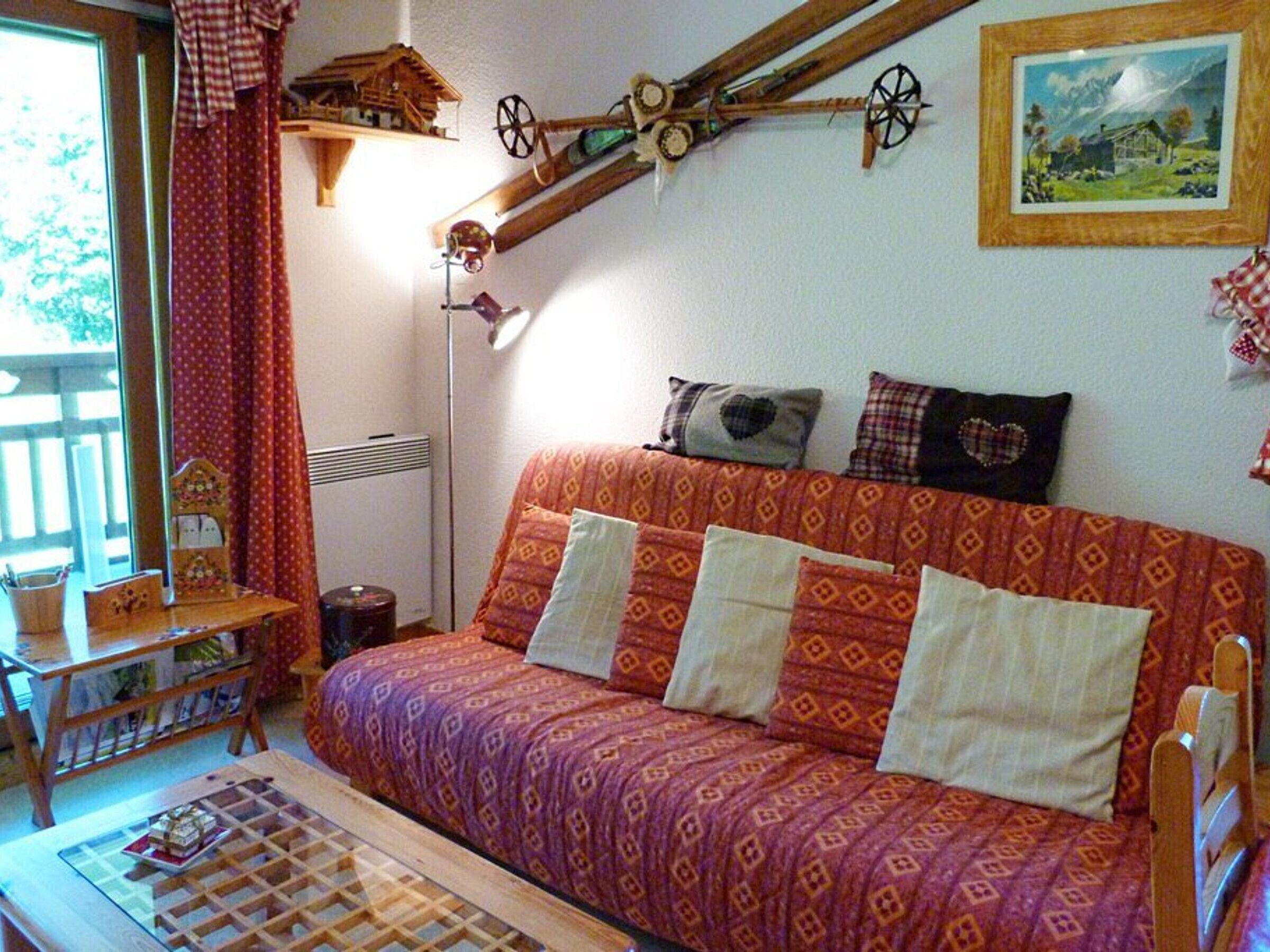 Una habitación acogedora con un sofá estampado, una mesita con un tablero de ajedrez y una estructura de madera montada en la pared.