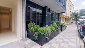 Un edifici modern amb grans finestres de vidre i un planter negre amb plantes verdes al davant.