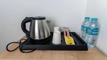 Bandeja com chaleira, xícaras e alimentos embalados sobre uma superfície de madeira.