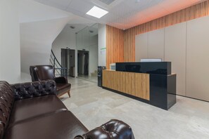 A modern reception area with a reception desk, leather seating, and a staircase leading to an upper level.