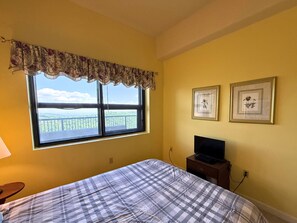 Ein Zimmer mit einem Bett, einem Fenster mit Blick, einem Fernseher und zwei gerahmten Bildern an der Wand.