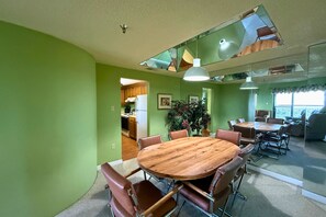 Ein Essbereich mit einem runden Holztisch, umgeben von Ledersesseln, einer großen Topfpflanze und einer modernen Deckenleuchte.