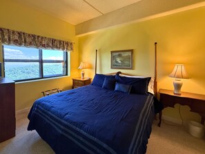 Una camera da letto con un letto grande, una finestra vista, un comodino con una lampada e un quadro appeso al muro.