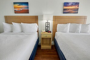 A hotel room with two beds, a nightstand with a lamp, a phone, and a digital clock. - Oceanfront Two Queen Room + Beach + Dog Friendly (Myrtle Beach)