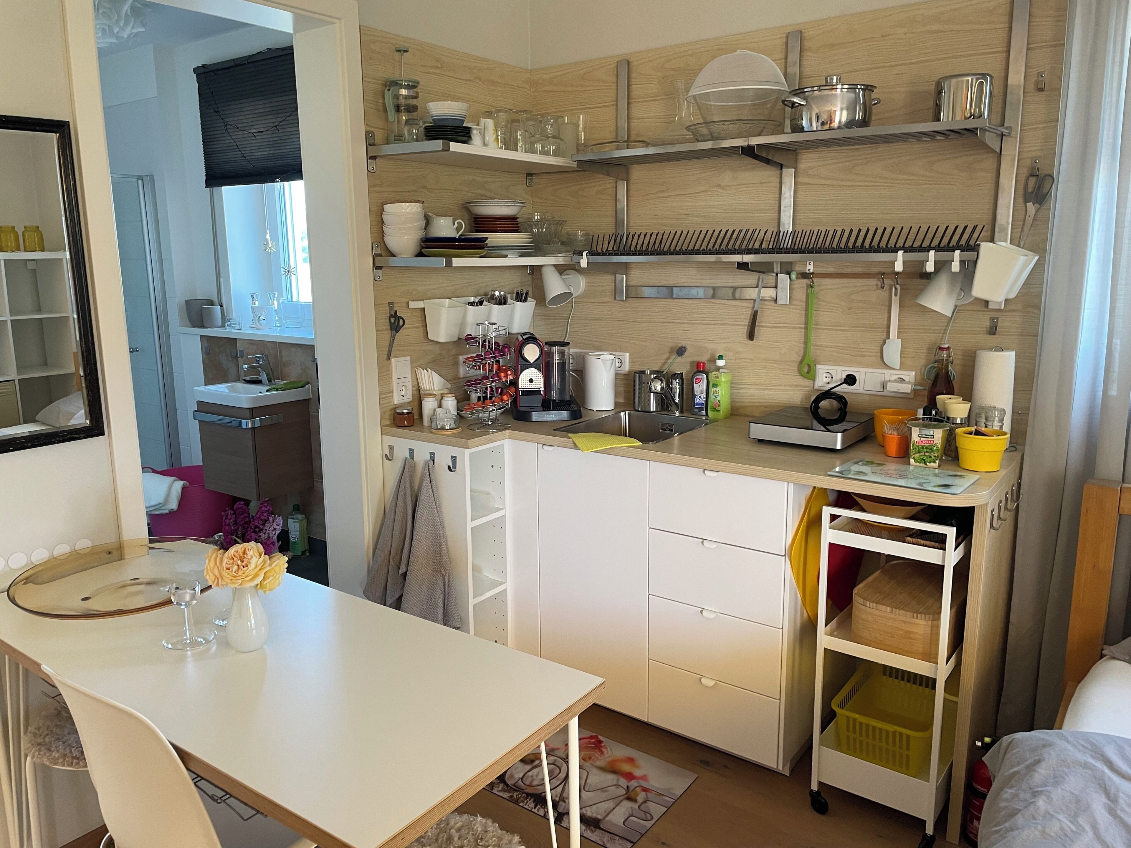 A modern kitchen with white cabinets, a wooden countertop, and various kitchen utensils and appliances.