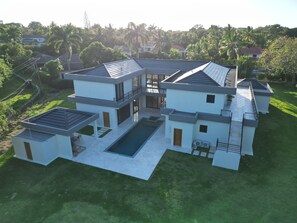 A modern two-story house with a flat roof, a swimming pool, and a well-maintained lawn. - Private 5BD Luxury Villa in Seahorse Ranch w/ Chef, Pool, and Beach Access (Sosúa)