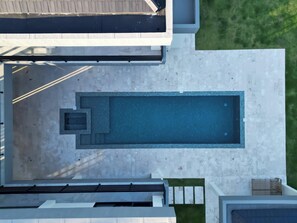 An aerial view of a modern building with a rectangular swimming pool, a covered patio area, and a well-maintained lawn. - Private 5BD Luxury Villa in Seahorse Ranch w/ Chef, Pool, and Beach Access (Sosúa)