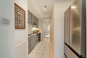 Eine moderne Küche mit Edelstahlgeräten, einer gefliesten Spritzschutzwand und einer gerahmten Kaffeediagramm an der Wand.