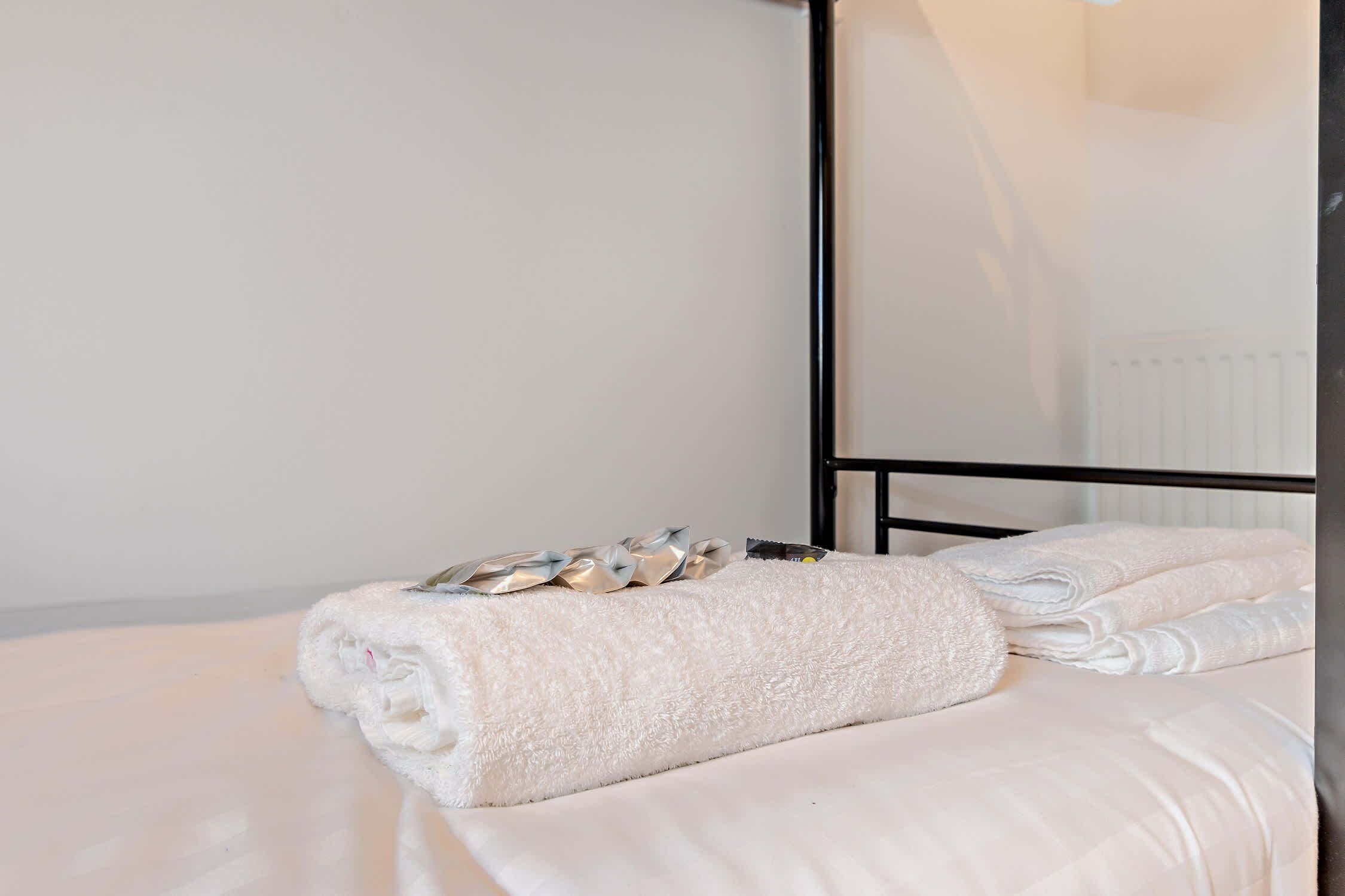 A hotel room with a bed, a folded towel, and a metal-framed mirror.