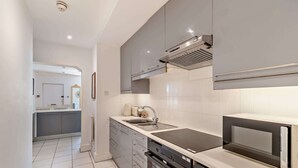 Een moderne keuken met grijze kastjes, een ingebouwde oven en een magnetron.