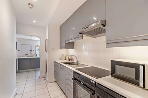 Eine moderne Küche mit grauen Schränken, einem eingebauten Backofen und einer Mikrowelle.