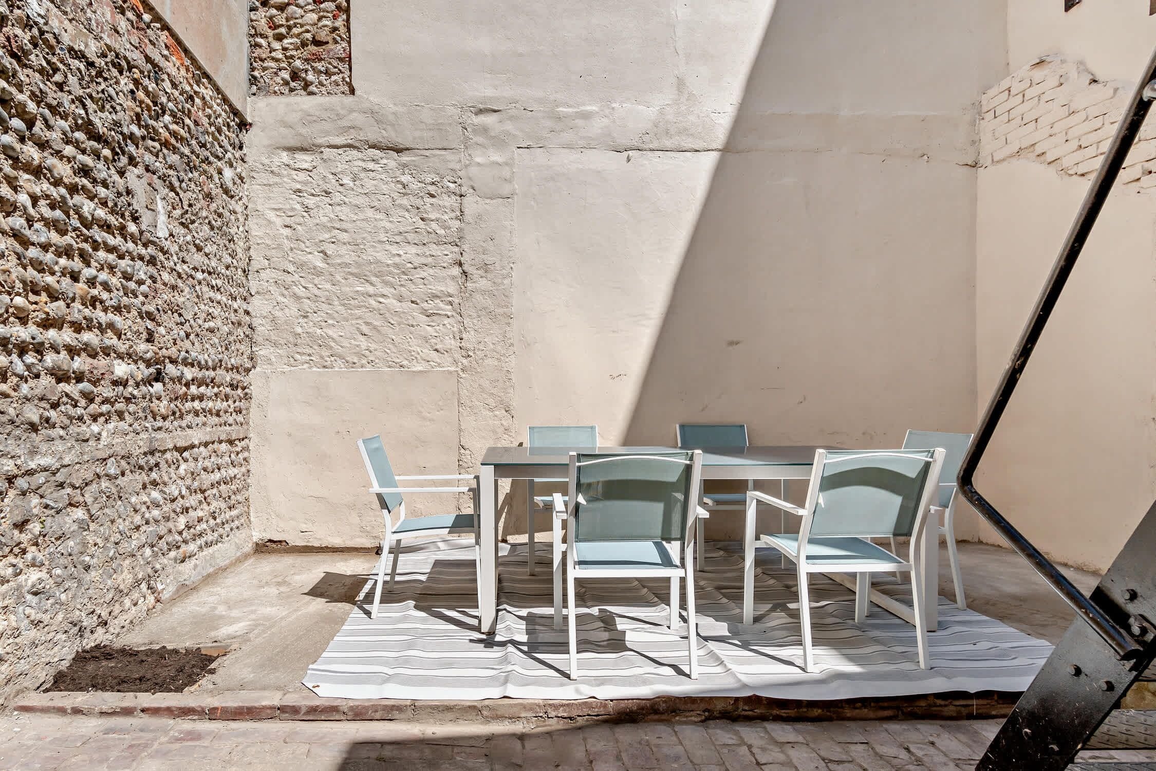 An outdoor seating area with a table and chairs, a brick wall, and a clear sky.