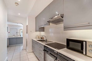 A modern kitchen with a built-in microwave, stove, and sink. - Host Stay - 37 Regency Square (Brighton)