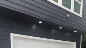 Uma porta de garagem com moldura branca, fixada em um edifício com revestimento escuro.