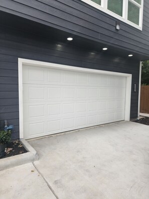 A garage door with a white frame, attached to a building with dark siding. - Charming 3-bedroom rooms with 2 full bath  house with AC in Houston area!  (Houston)