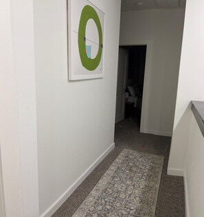 A hallway with a patterned rug, a framed artwork on the wall, and a doorway leading to another room. - Charming 3-bedroom rooms with 2 full bath  house with AC in Houston area!  (Houston)