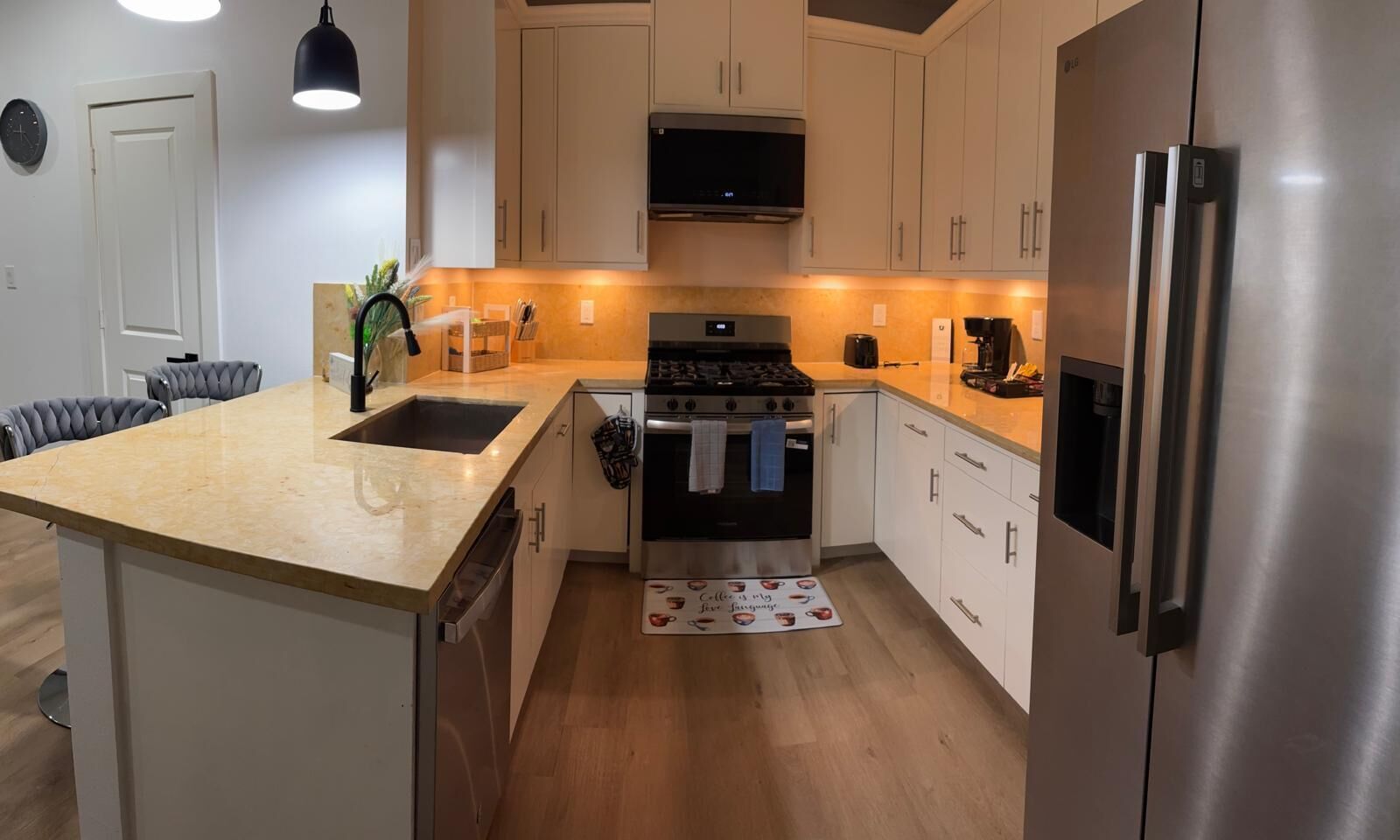 A modern kitchen with a central island, stainless steel appliances, and white cabinetry.