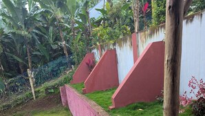Eine Rasenfläche mit einer rosa Wand und einem hölzernen Pfosten.