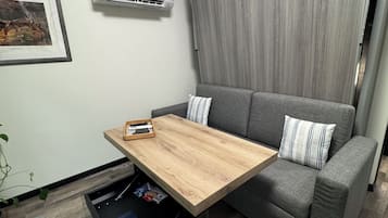 A modern living room with a gray sofa, a wooden coffee table, and a wall-mounted air conditioner.