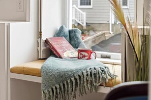 Un rincón acogedor para leer, con un libro, una taza y una manta tejida.