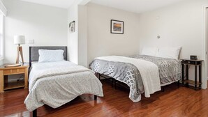 A bedroom with two beds, a bedside table with a lamp, and a framed picture on the wall. - Waterfront - Sauna -steps To Beach! (Saco)